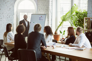 Wall Mural - Motivated. Group of young business professionals having a meeting. Diverse group of coworkers discuss new decisions, plans, results, strategy. Creativity, workplace, business, finance, teamwork.