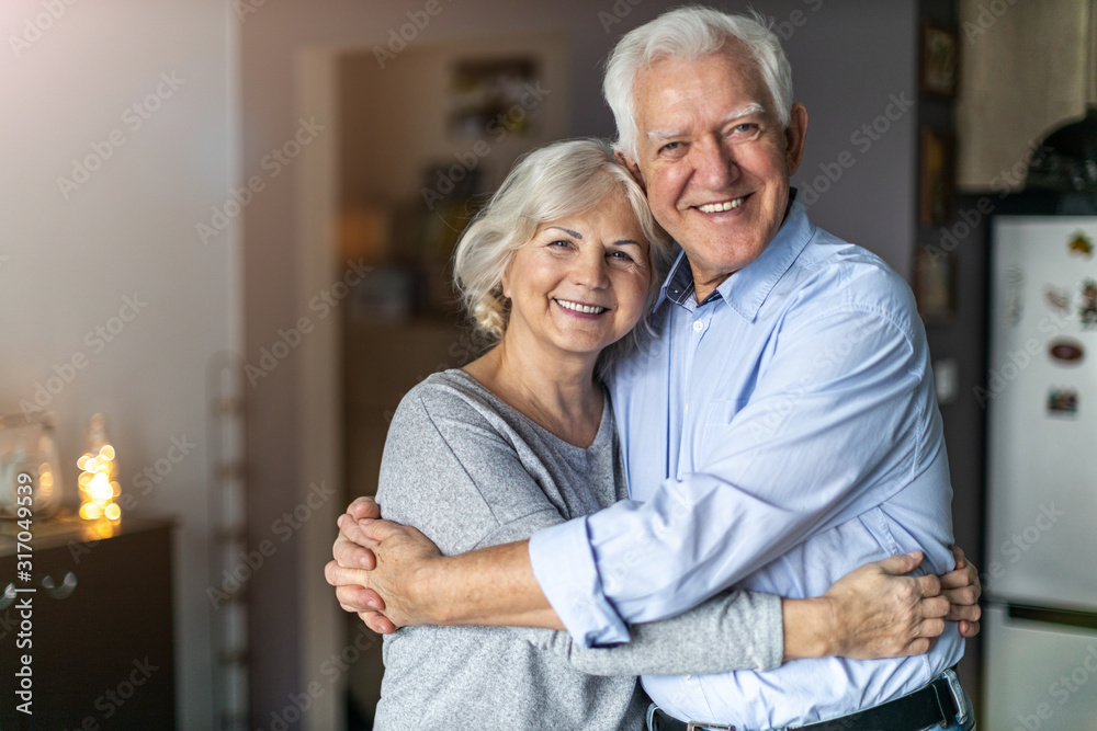 Happy senior couple embracing in their home  - obrazy, fototapety, plakaty 
