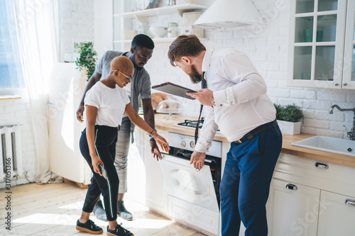 Fotomural Confident estate agent showing kitchen to African American thoughtful couple