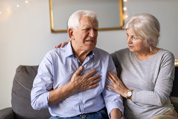 Wall Mural - Senior woman helping her husband with chest pain