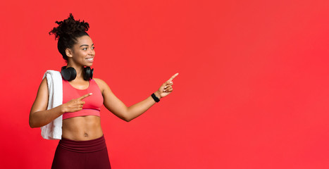 Wall Mural - Excited sporty girl with headset pointing at copy space