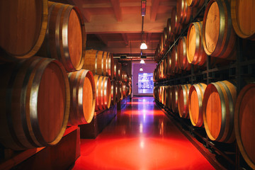 Fototapete - Oak barrels with wine in dark cellar. Modern production of wine with the observance of age-old traditions. Noises and large grain - stylization under the film. Soft focus.