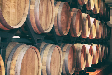 Fototapete - Oak barrels with wine in dark cellar. Modern production of wine with the observance of age-old traditions. Noises and large grain - stylization under the film. Soft focus. close-up