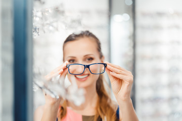 Wall Mural - Woman being satisfied with the new eyeglasses she bought in the store