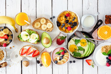 Healthy Breakfast Table Scene With Fruits, Yogurts, Oatmeal, Cereal, Smoothie Bowl, Nutritious Toasts And Egg Skillet. Top View Over A White Wood Background.