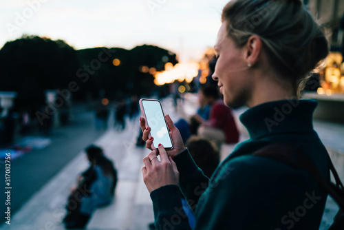 Cuadros en Lienzo Glad female tourist looking on smartphone during walk around city