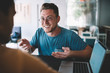 © BullRun - Happy young businessman having meeting with colleague in cafe