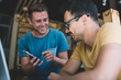 © BullRun - Cheerful young male friends having fun with smartphone in cafe