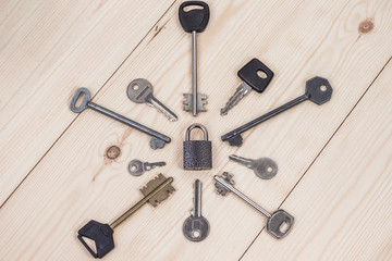 Padlock in the center and a lot of keys around on a wooden surface. Security, secret protection concept