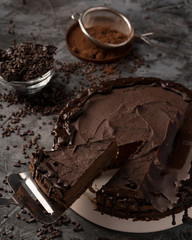 Raw chocolate cheesecake on dark grey background. Healthy organic dessert pie. Cacao and chocolate around