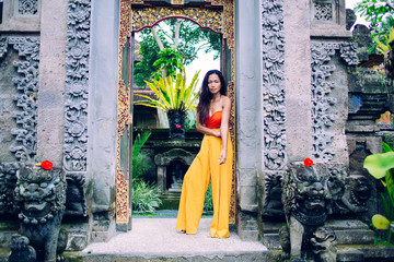 Ethnic female in bright clothes near temple