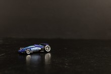 Selective Focus Shot Of A Blue Toy Sports Car On A Black Surface