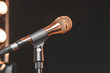 © Masarik - The golden microphone mounted on the stand rack, on black background, with stage lights. Studio, isolated.