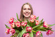 © Богдан Маліцький - girl holds and sniffs a bouquet of flowers on a pink background, a beautiful woman with tulips