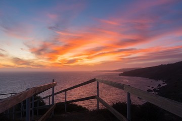 Poster - Breathtaking sunset over the calm ocean surrounded by hills