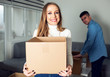 © Novak - Happy young woman holding carton box in new home