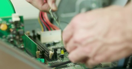 A computer technician removing random access memory or RAM from a desktop computer he is repairing.