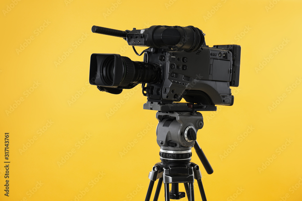Modern professional video camera on yellow background - obrazy, fototapety, plakaty 
