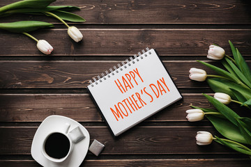 Wall Mural - White Tulip flowers with a Cup of coffee on a wooden table. Greeting card with lettering Happy Mother's Day