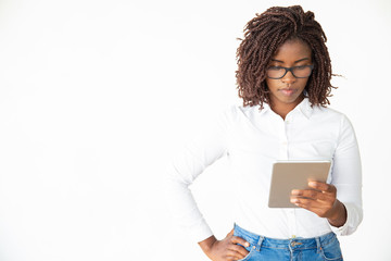 serious woman in eyeglasses using tablet pc. front view of young african american businesswoman stan