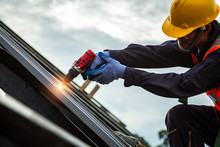[Construction Roof] Roofer Worker In Protective Uniform Wear And Gloves, Construction Worker Install New Roof,Roofing Tools,Electric Drill Used On New Roofs With Metal Sheet.