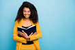 © deagreez - Photo of pretty dark skin wavy lady holding love story novel book eyes closed imagine herself main character wear specs stylish yellow suit blazer isolated blue color background