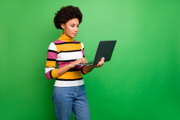 Wall Mural - Profile photo of beautiful dark skin wavy lady holding notebook browsing reading news serious professional broker wear casual striped jumper jeans isolated green color background