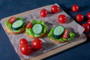 Bread with cucumber, lettuce and tomatoes. Sandwiches on a dark background. Selective focus. Healthy food, diet and nutrition concept