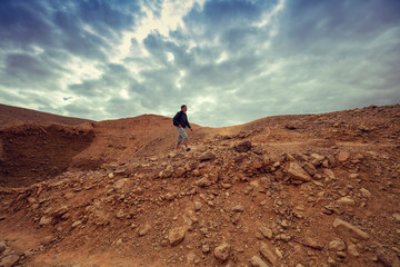 Wall Mural - Human hiking in a desert. Desert landscape with dramatic cloudy sky