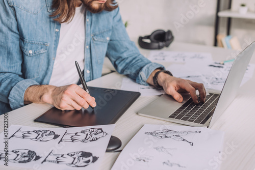 Fotografía cropped view of animator using gadgets near sketches