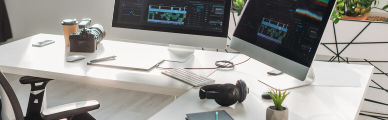 panoramic shot of computer monitors with storyboard near digital camera on table