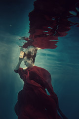 Wall Mural - Portrait of a girl in a red dress under water