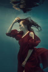 Wall Mural - Portrait of a girl in a red dress under water