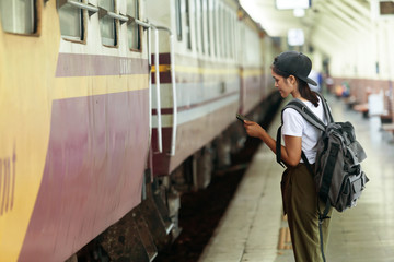 asian girl checking map on phone with backpack, travel by train, destination nature trip in summer