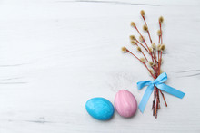 Easter Eggs In Blue And Pink, Willow Branches Tied With A Blue Ribbon On A White Background, Top View, Space For Text