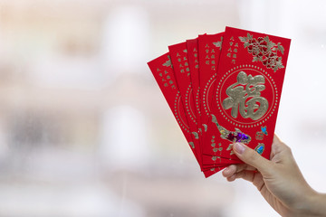 Hand holding red envelope or Ang pao. Chinese Lunar New Year celebrations concept, Chinese word mean Lucky and Successful