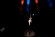 spotlights on acrobat performing acrobatic exercise on metallic pole in circus