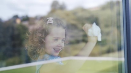 Wall Mural - Cute small girl helping with housework indoors at home, cleaning window.