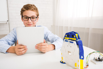 Poster - Boy controling robot with tablet at stem educational lesson
