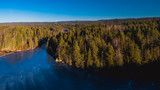 Fototapeta Na ścianę - Widok z lotu ptaka na zamarznięte jezioro po środku Skandynawskiego lasu