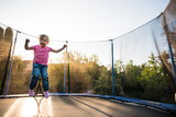 Fototapeta  - Happy kid playing on trampoline in the backyard