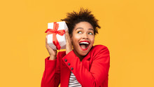 Happy Black Girl Shaking Gift Box Near Ear