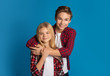 © Prostock-studio - Happy siblings, brother and sister hugging and posing over blue background