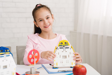 Wall Mural - Happy schoolgirl showing diy robot at stem lesson