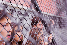 Friends Looking Through Chain Link Fence