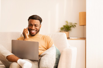 Canvas Print - Guy Working On Laptop Chatting On Phone Sitting At Home