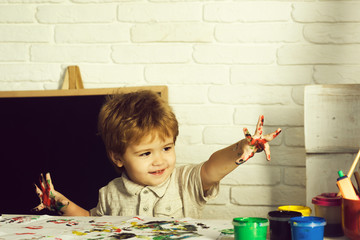 Child and creative education. Boys and multi colored paints on hands.