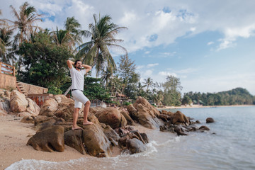 Wall Mural - A man on the tropical coast in stones by the sea.