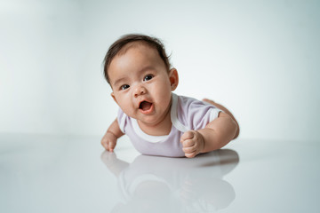 baby laying on her belly. tummy time cute baby in studio portrait on white background