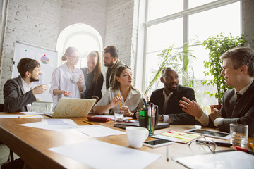 Wall Mural - Together. Group of young business professionals having a meeting. Diverse group of coworkers discuss new decisions, plans, results, strategy. Creativity, workplace, business, finance, teamwork.